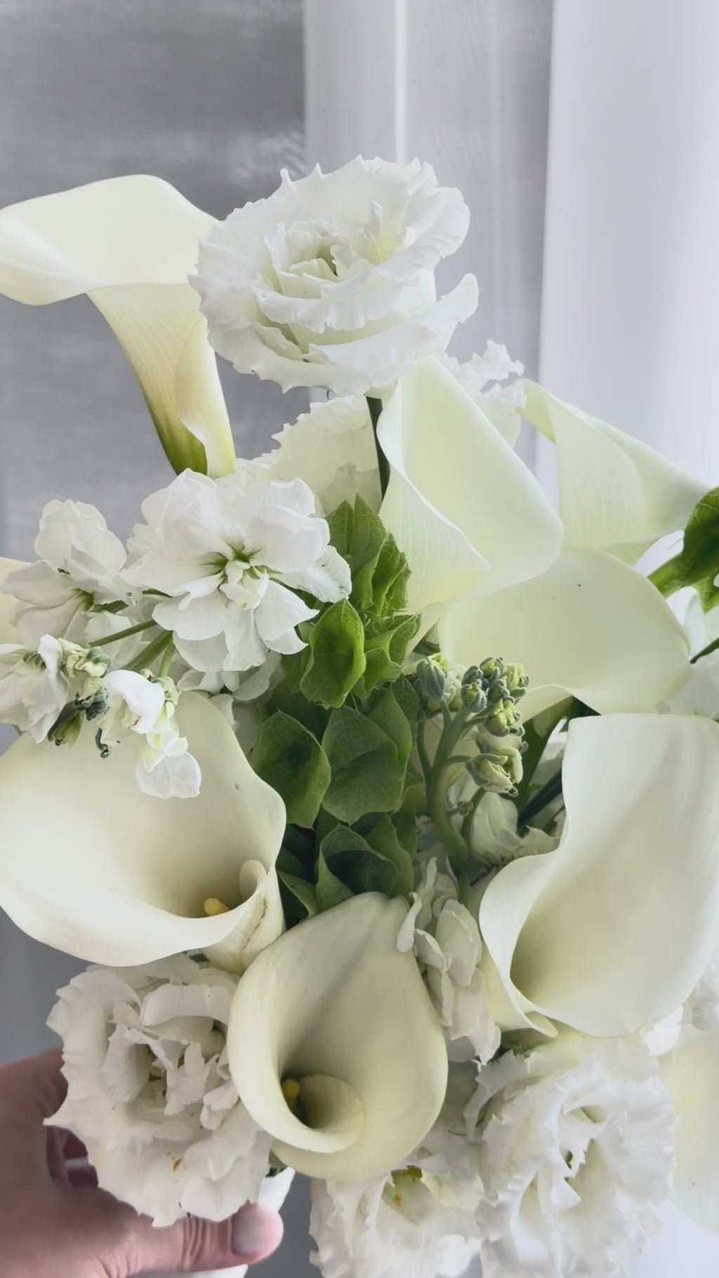 White bridal bouquet with calla lilies, lisianthus, and fresh greenery