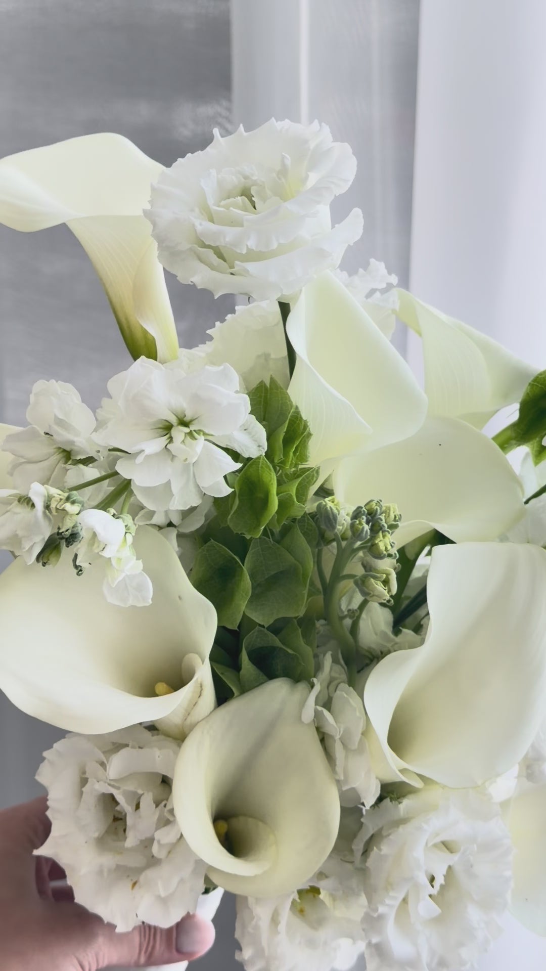 White bridal bouquet with calla lilies, lisianthus, and fresh greenery