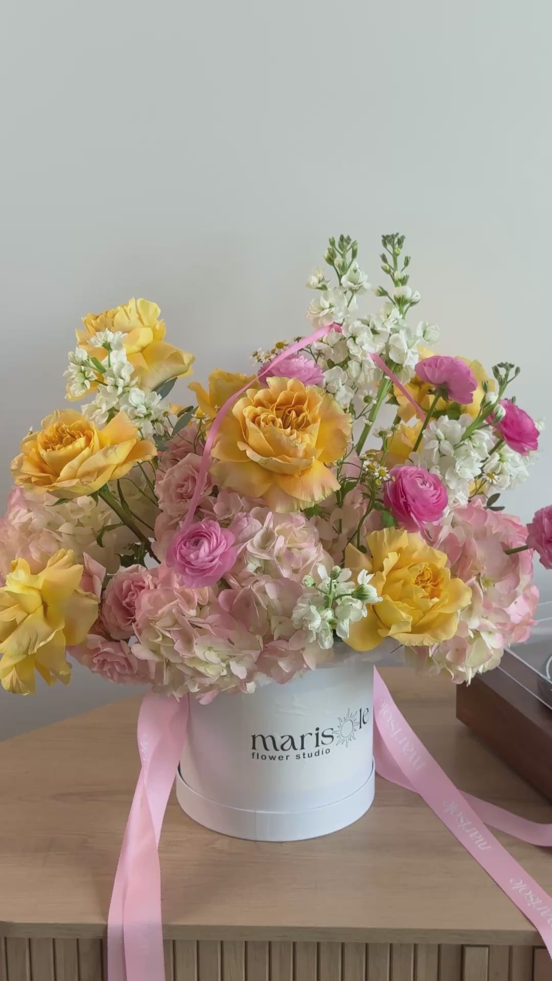 Video of Pink Lemonade Box with yellow garden roses, pink ranunculus, blush hydrangeas, white stock, and chamomile in a Marisole Flower Studio box.
