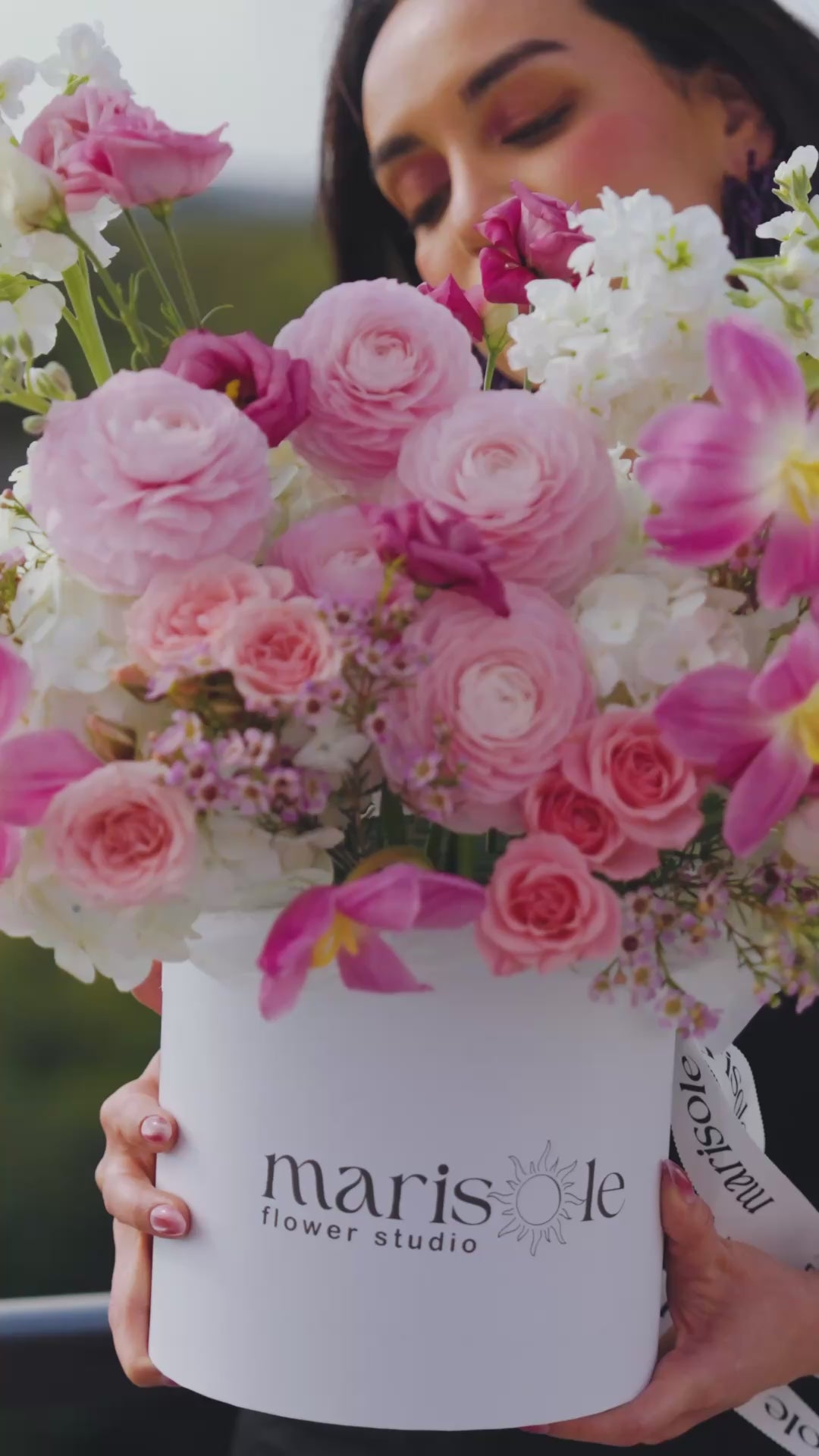 Video of a woman holding a pink flower box with soft pink roses, hydrangeas, and pastel blooms in Marisole Flower Studio styling.