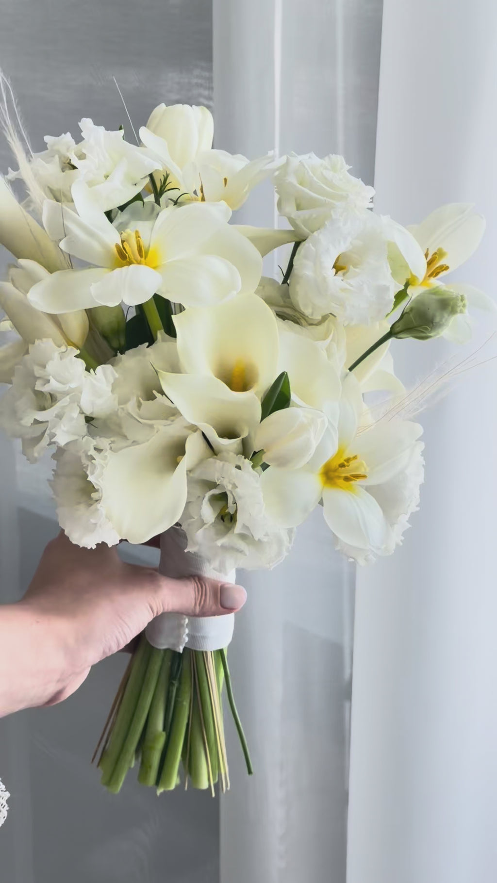 White wedding bouquet with calla lilies, tulips, ranunculus, and lisianthus