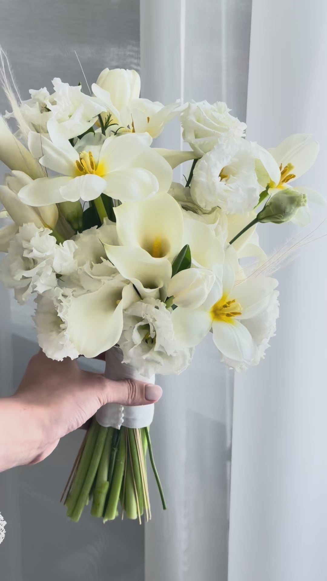 White wedding bouquet with calla lilies, tulips, ranunculus, and lisianthus
