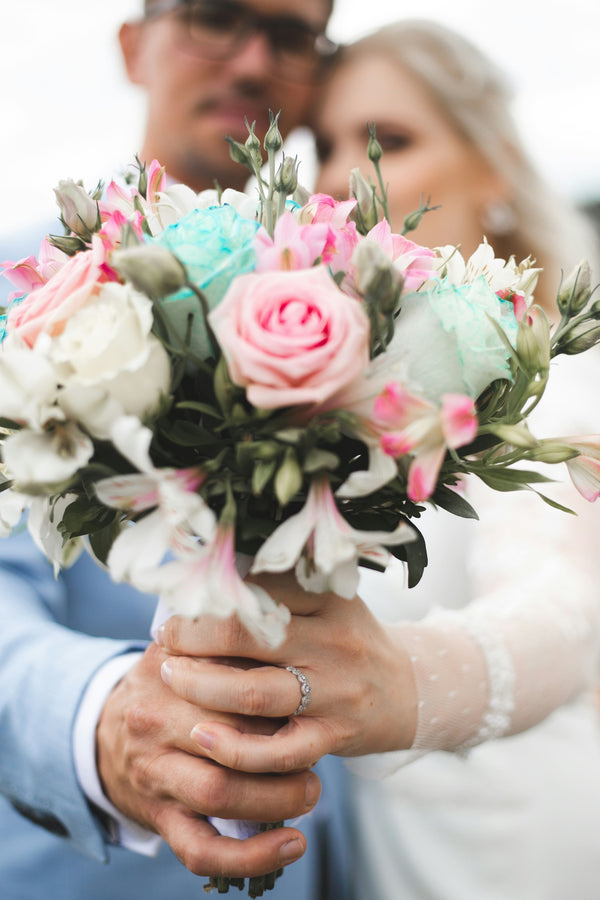 Bouquet of flowers held by a couple with a blurred background