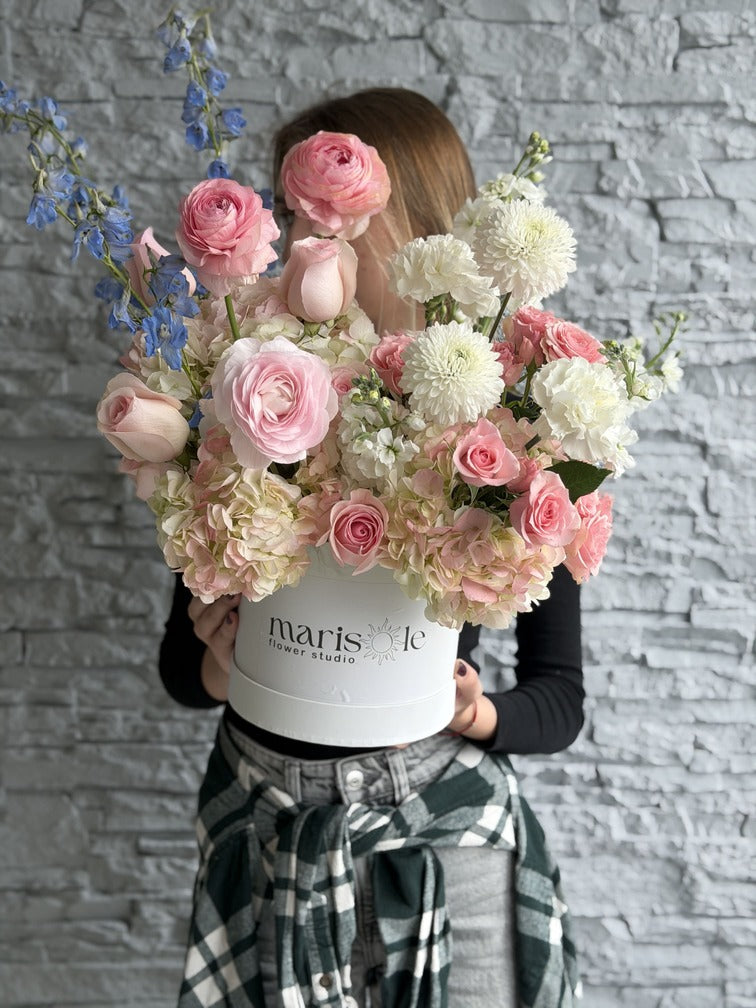 Person holding a large bouquet of flowers in front of a gray brick wall