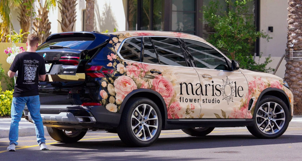 SUV with floral and branding design, person standing next to it