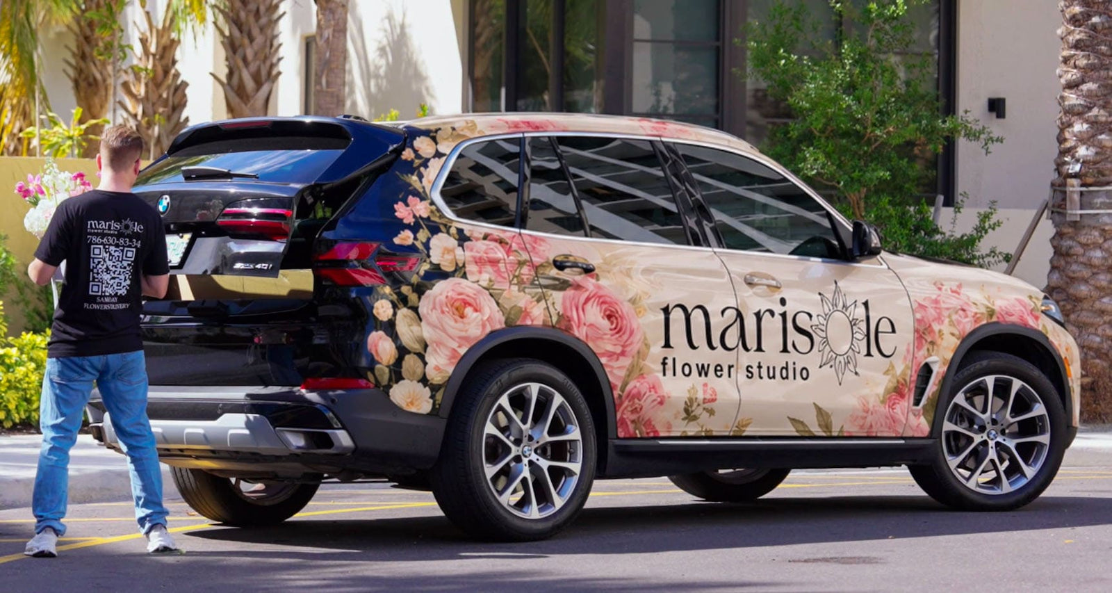 SUV with floral and branding design, person standing next to it