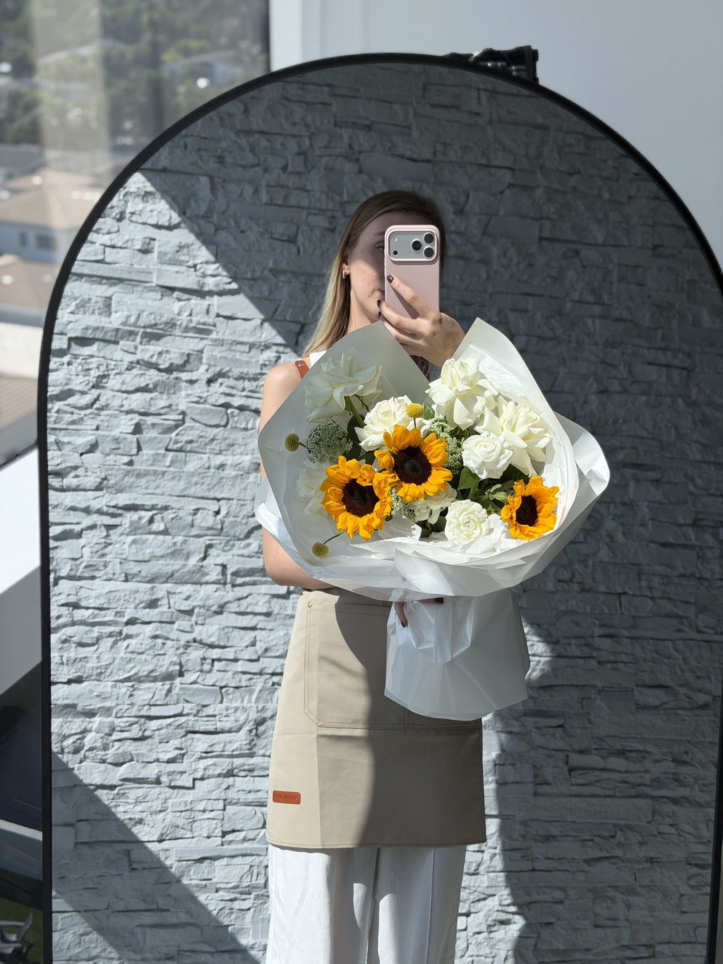 Person holding a bouquet of flowers in front of a gray stone wall