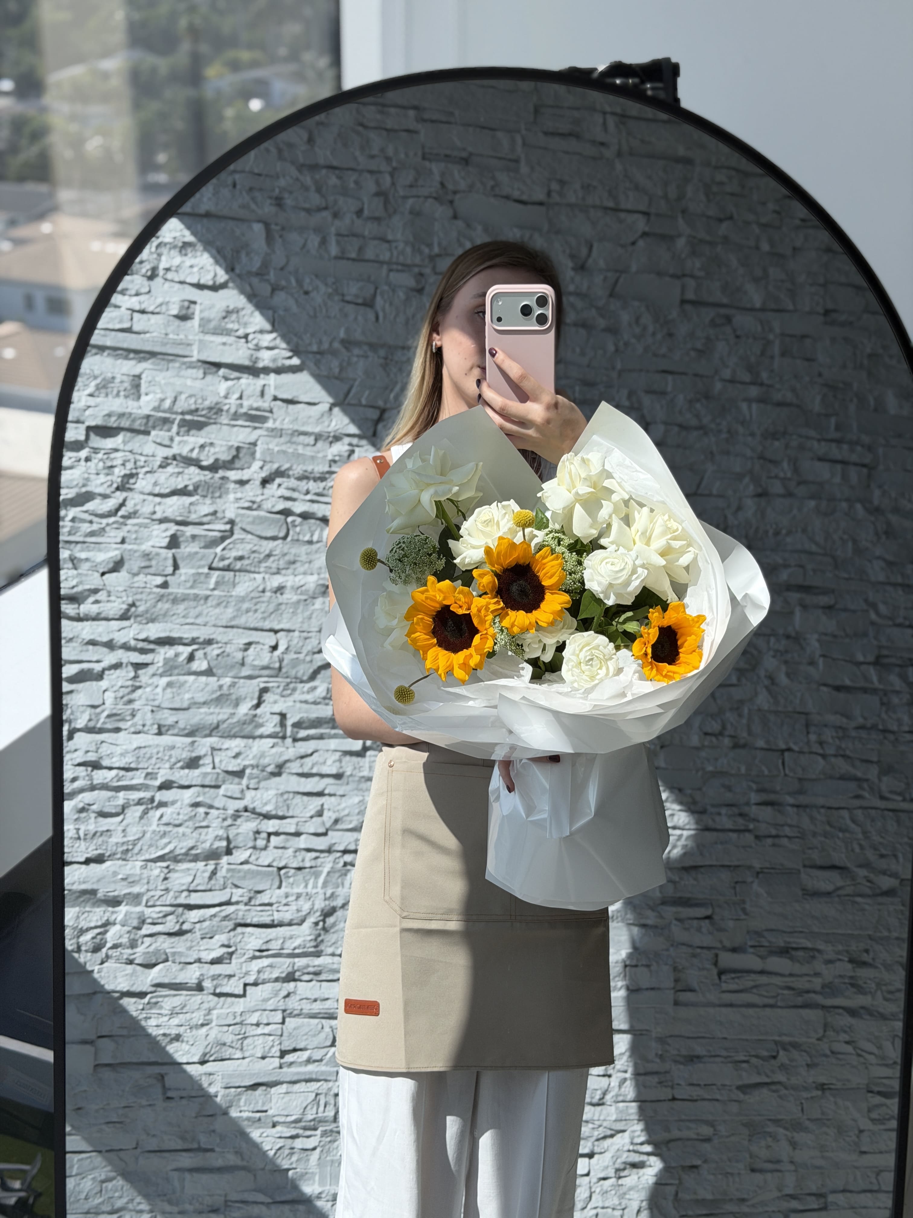 Person holding a bouquet of flowers in front of a gray stone wall