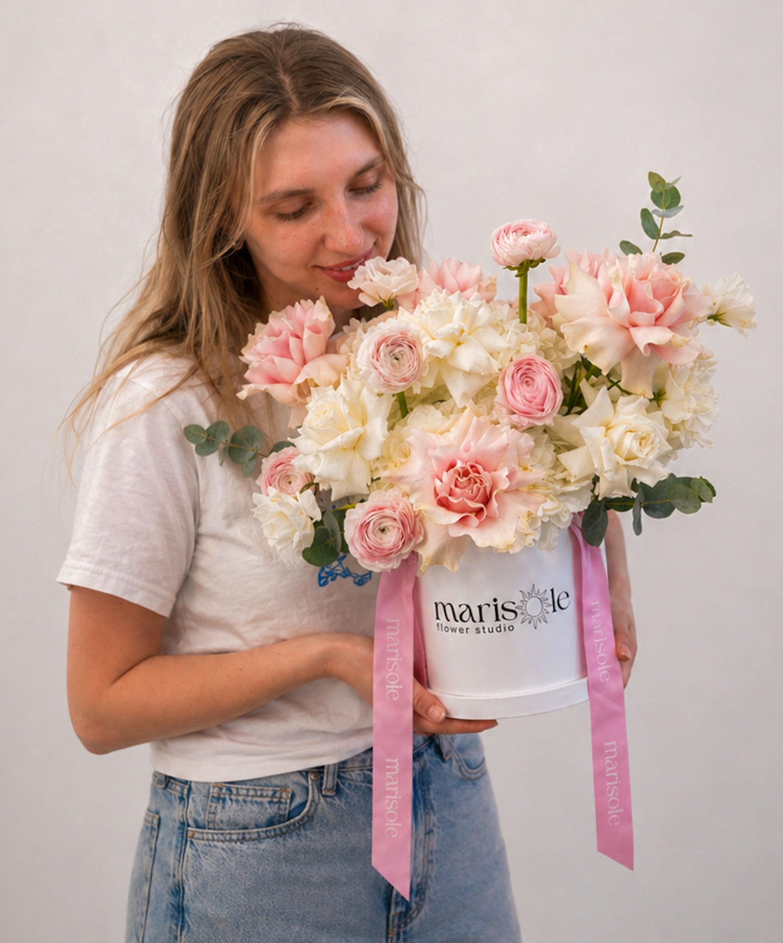 Woman holding a bouquet of flowers with 'marisole flower studio' branding.