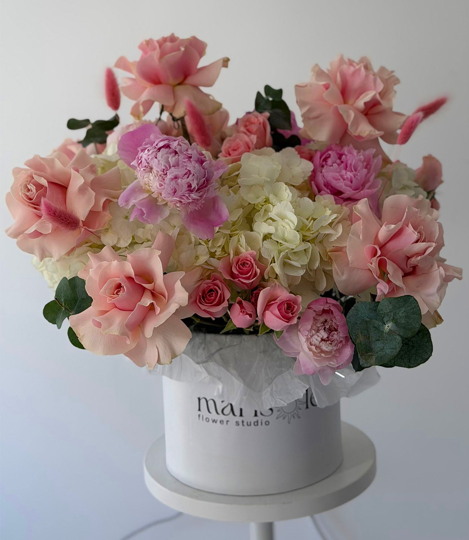 Bouquet of pink and white flowers in a white box with 'Marisole Flower Studio' branding on a light gray background.