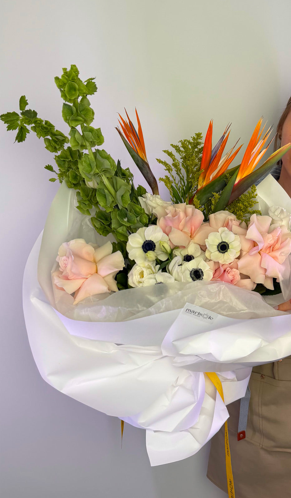 Bouquet of flowers with greenery and orange bird-of-paradise against a white background