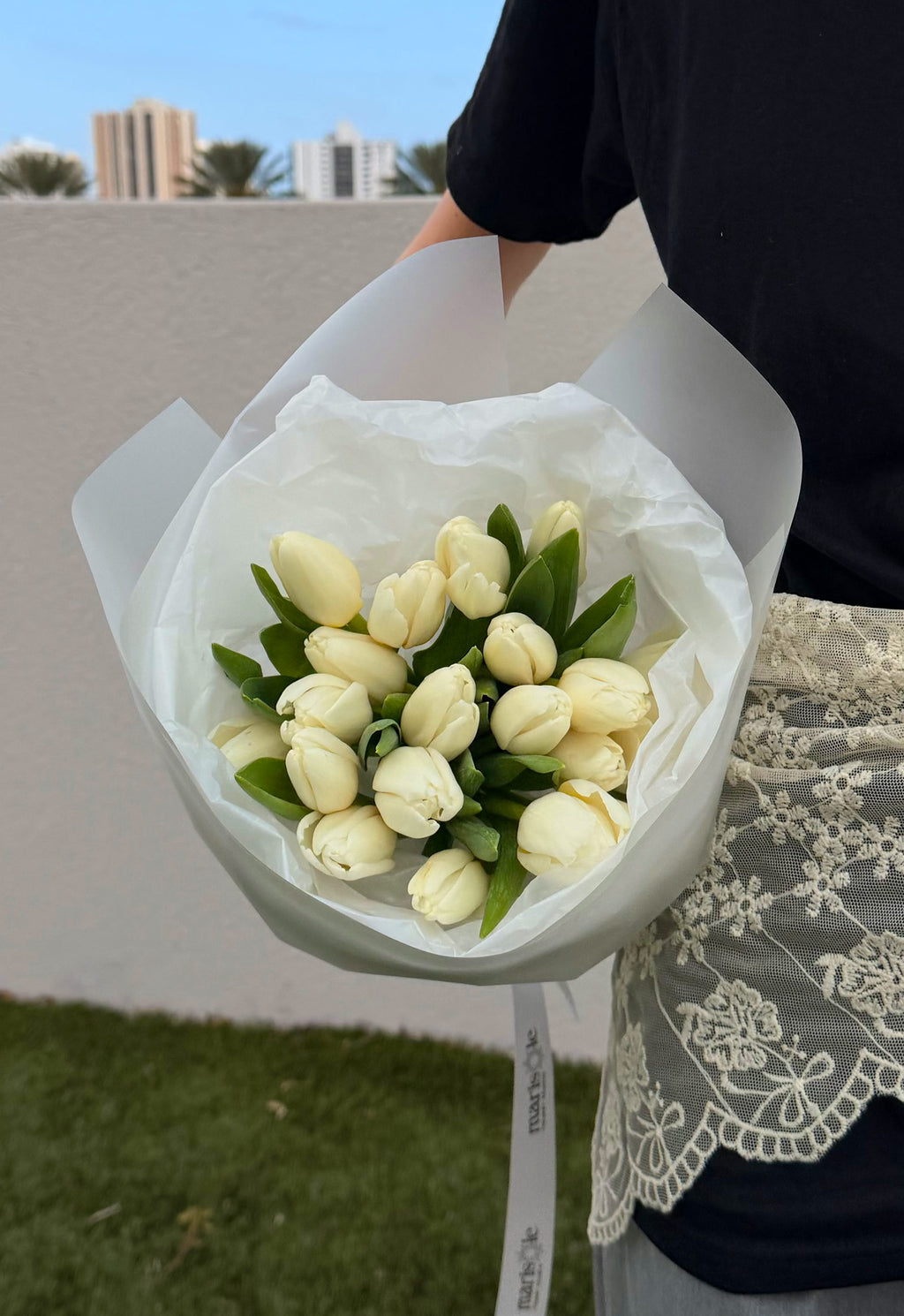Bouquet of white tulips held by a person with a blurred background