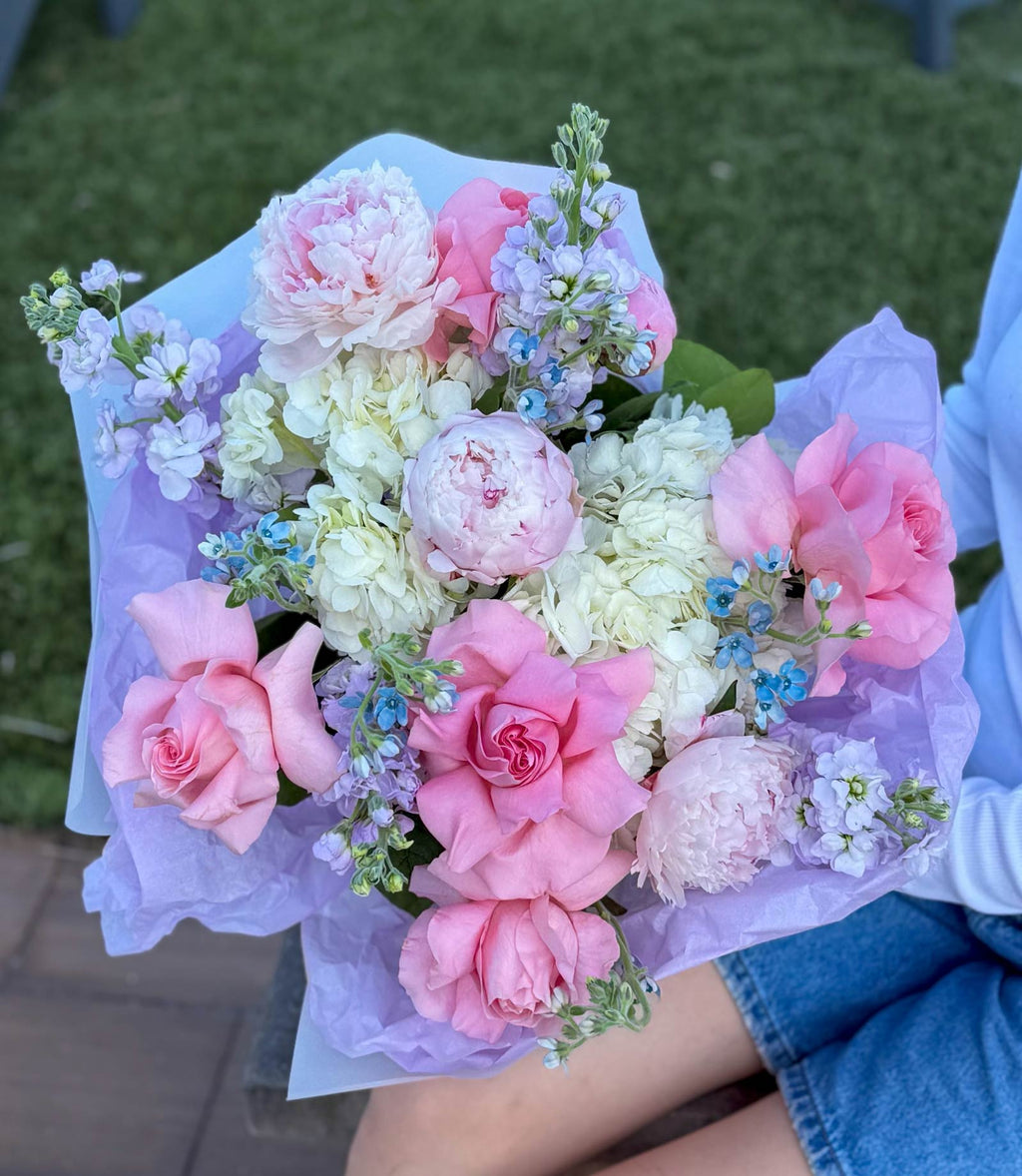 Bouquet of pink and white flowers held by a person with a blurred background
