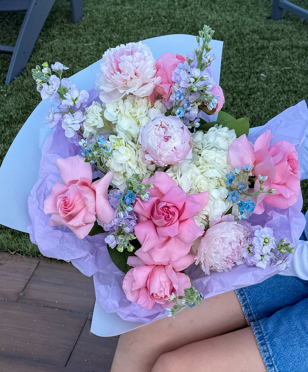 Bouquet of pink and white flowers held by a person on grass