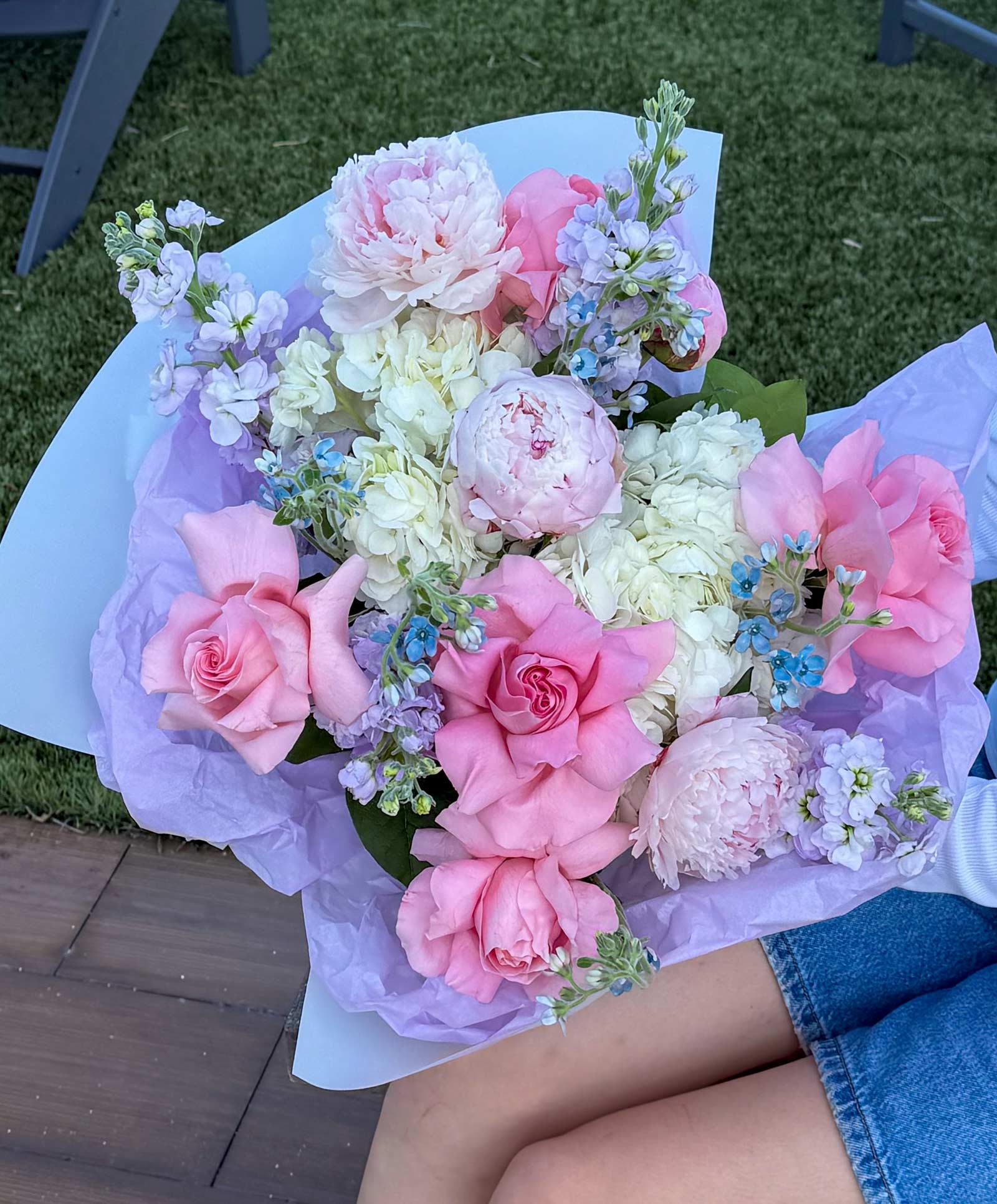 Bouquet of pink and white flowers held by a person on grass