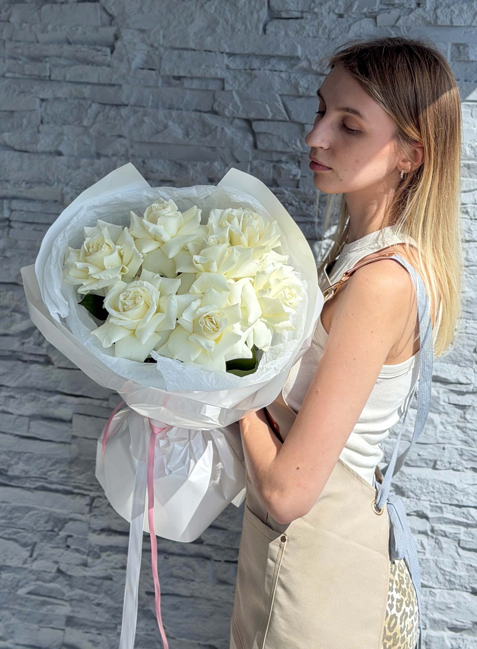 Side view of a woman holding a White French Roses bouquet with soft white blooms and elegant wrapping.